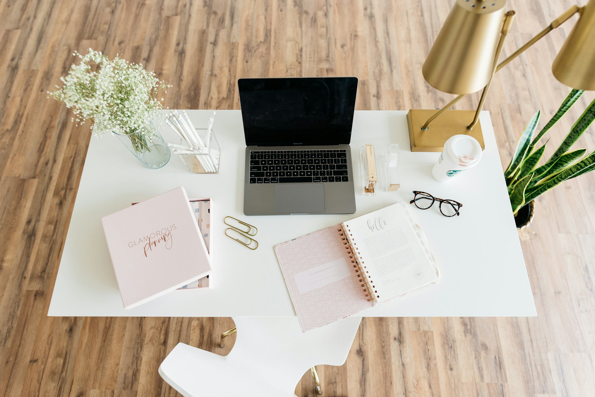 Bureau blanc vu de dessus avec laptop, carnets et fleurs