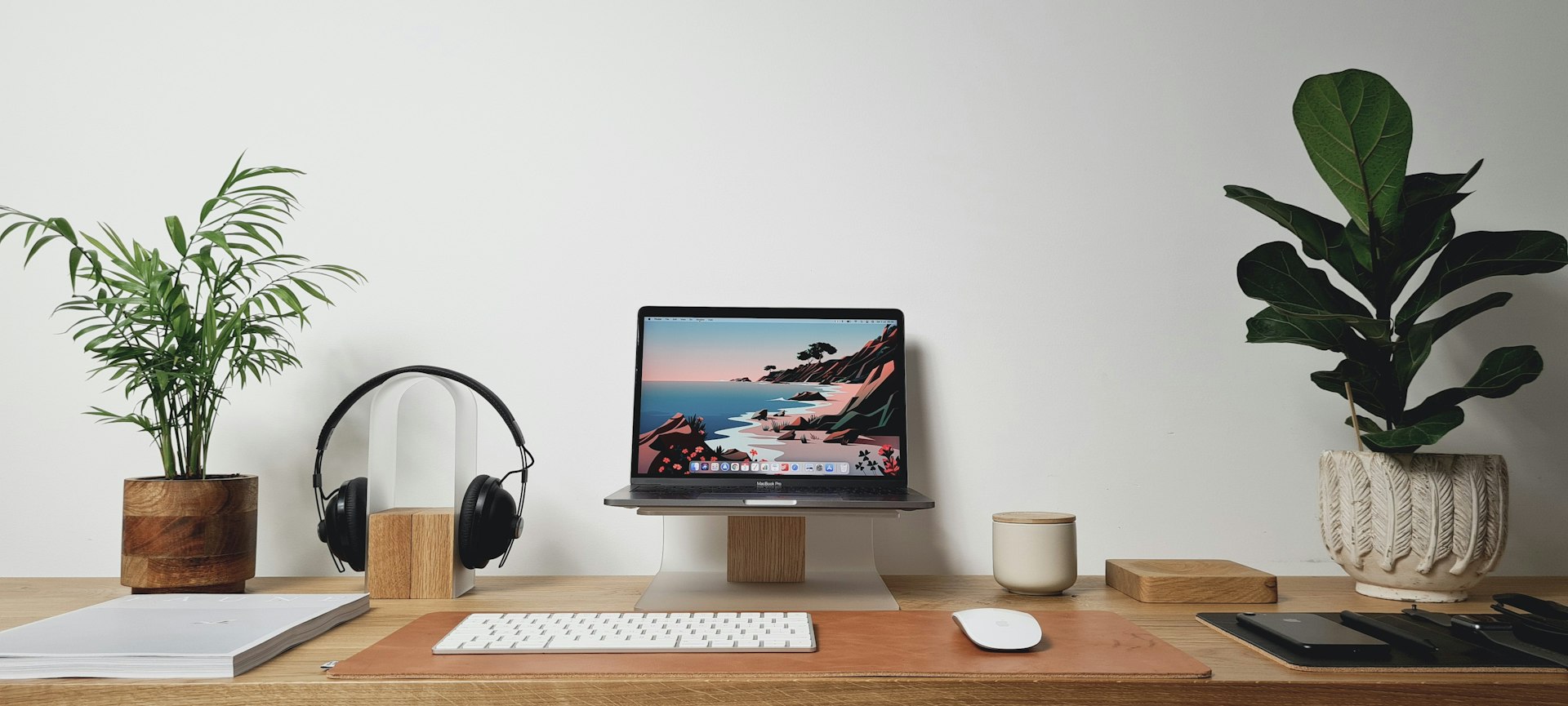 Bureau en bois avec laptop surélevé, clavier externe et plantes